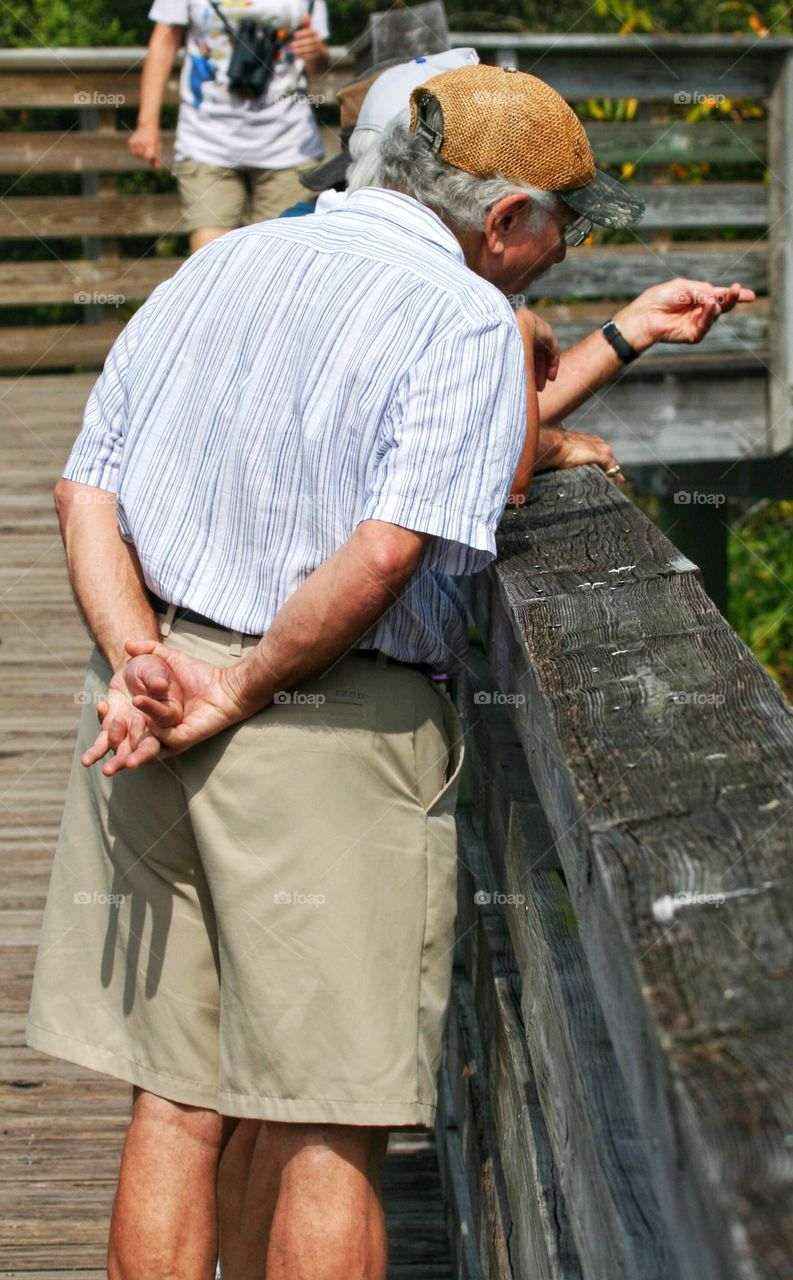 An elderly gentleman enjoying nature on a boardwalk trail. 


