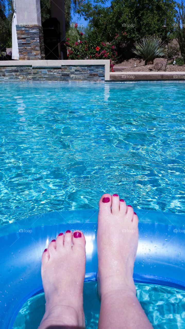 Female legs and inflatable swim ring in the pool