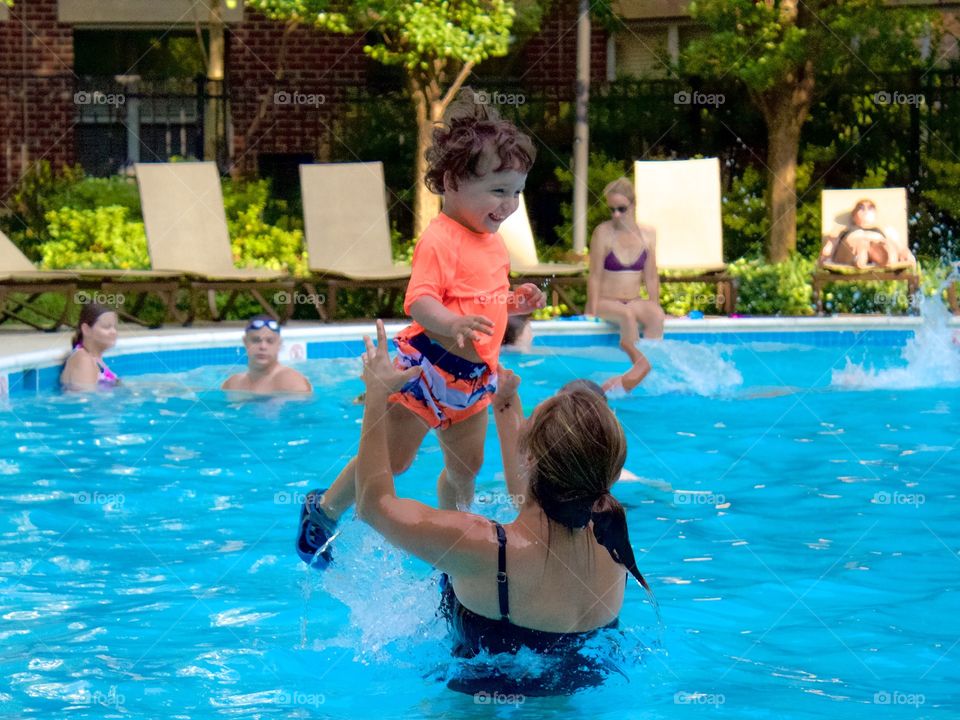 A mother and her toddler son playing in the swimming pool 