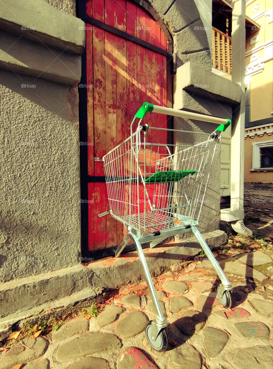 Shopping cart attached to a red wooden door on an old street