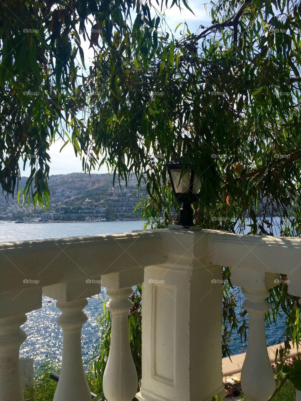 Lantern on the fence of hotel with view on the sea under a tree