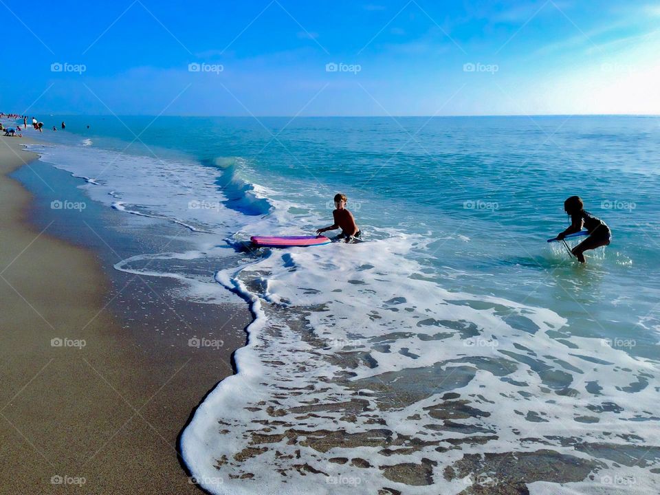 Children on the beach playing with there  boogie board.