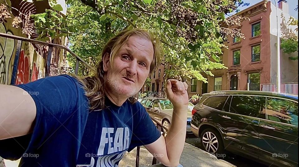 This is „Timothy Trespas“, my significant other for so many years it evades counting sitting on our favorite stoop on „Waverly Av“ off „Fulton St“ in „Fort Greene“, Brooklyn smoking a cigarette, smiling and emoting. 2022. Hypnotic Productions