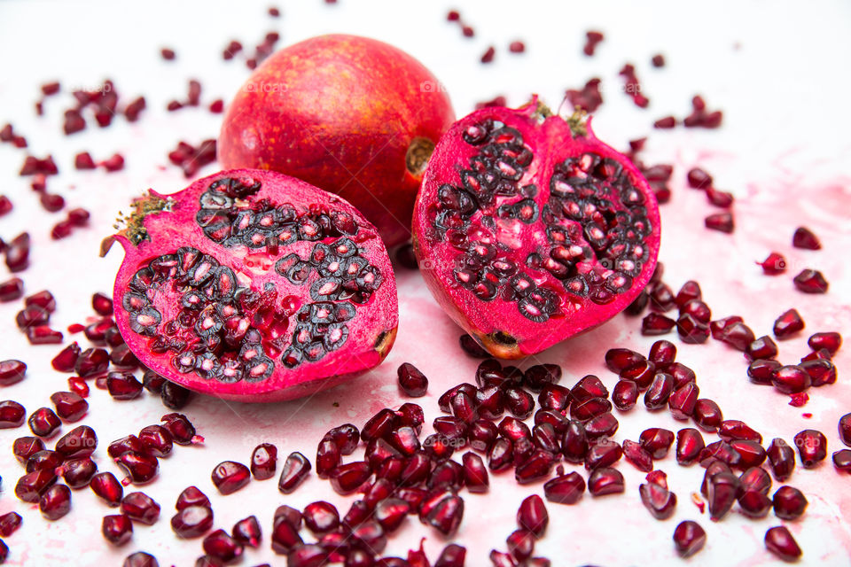 Fresh juicy summer fruits. Whole, cut and pieces of fresh pomegranates. Love this red fruit for summer days! Close up on a white background.