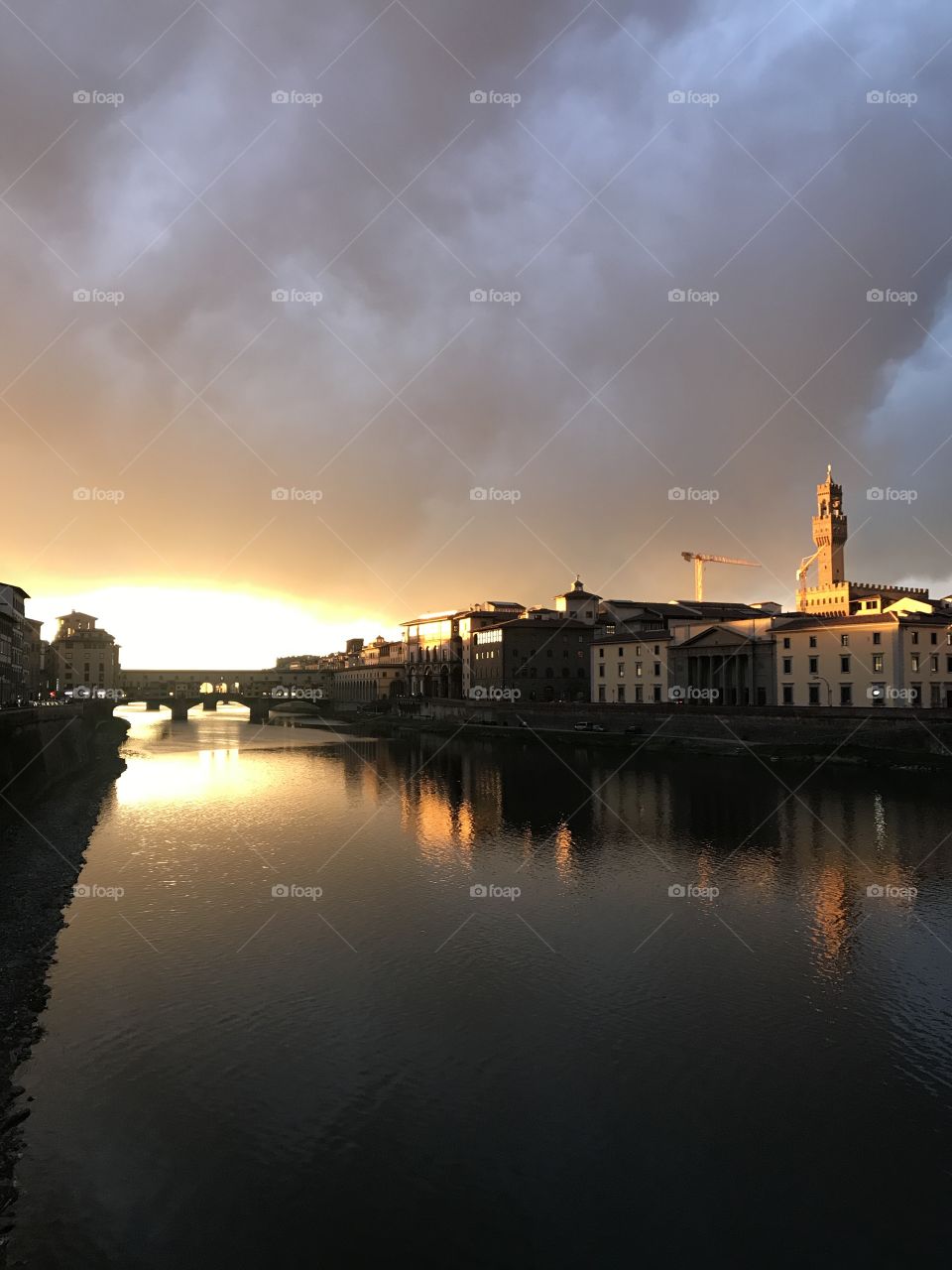 The beautiful evening sun setting over the Ponte Vecchio with rays of sun hitting against the rooftops.