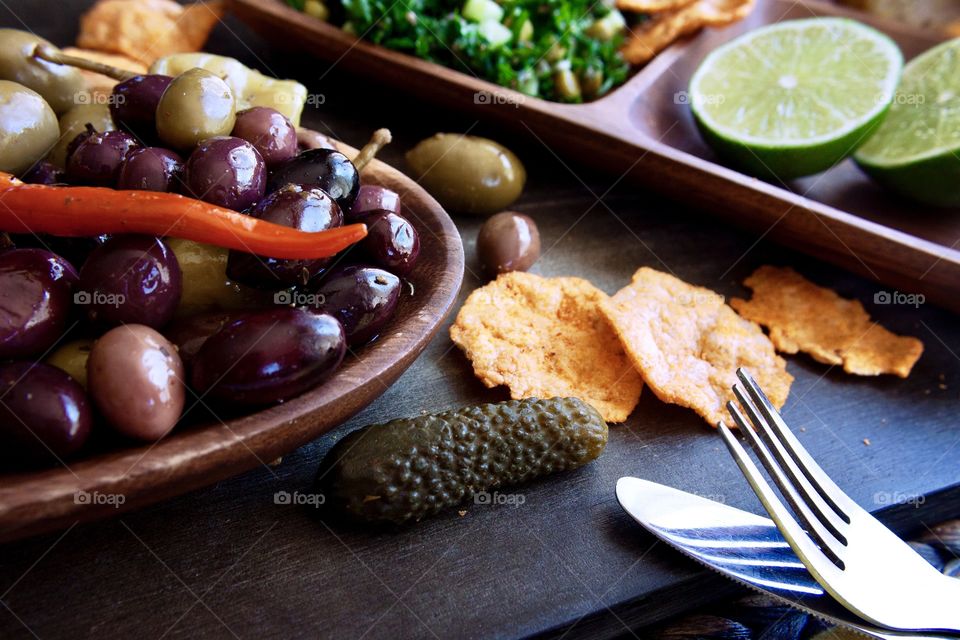 Healthy green salad with lime, olives and popped protein chips in wooden serving bowls.