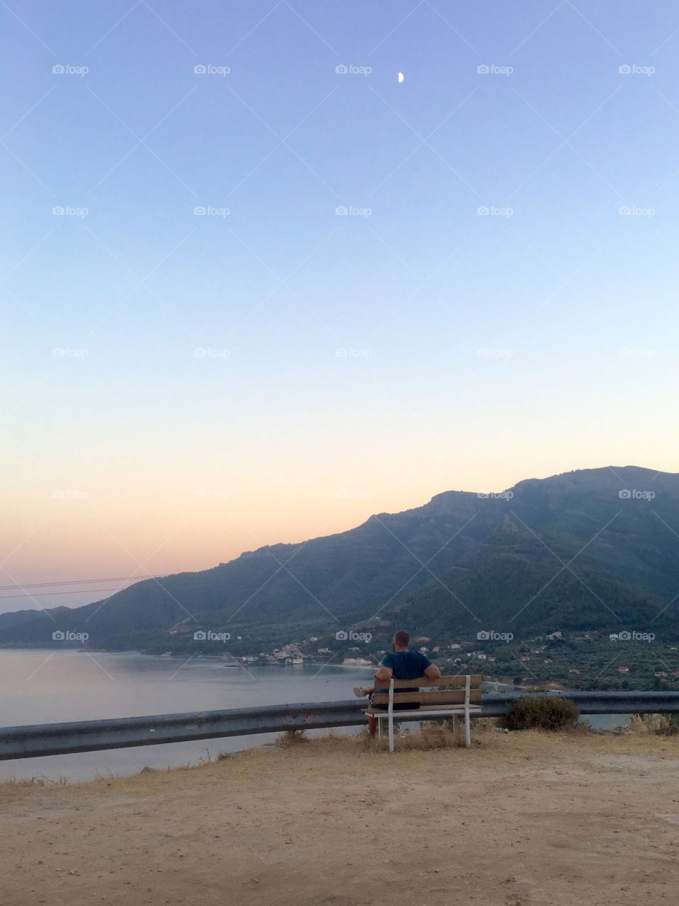 Man sitting on bench watching sunset on Thassos island