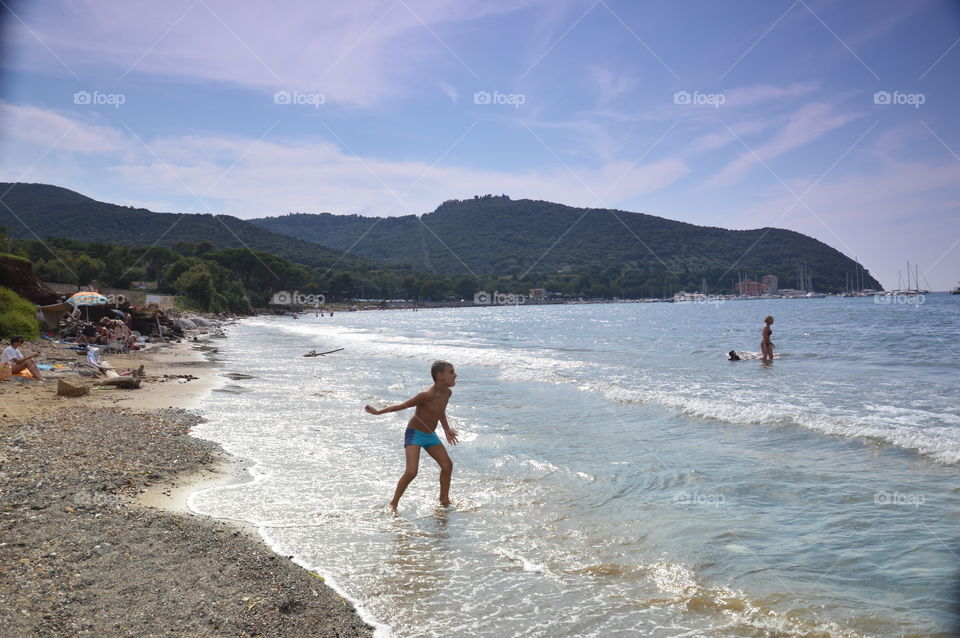 child throwing stone at sea