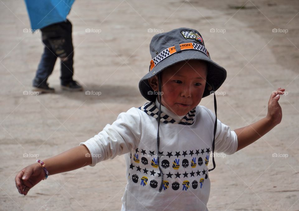 little tibetan boy playing in the yard of buddhist monastery in shigatse