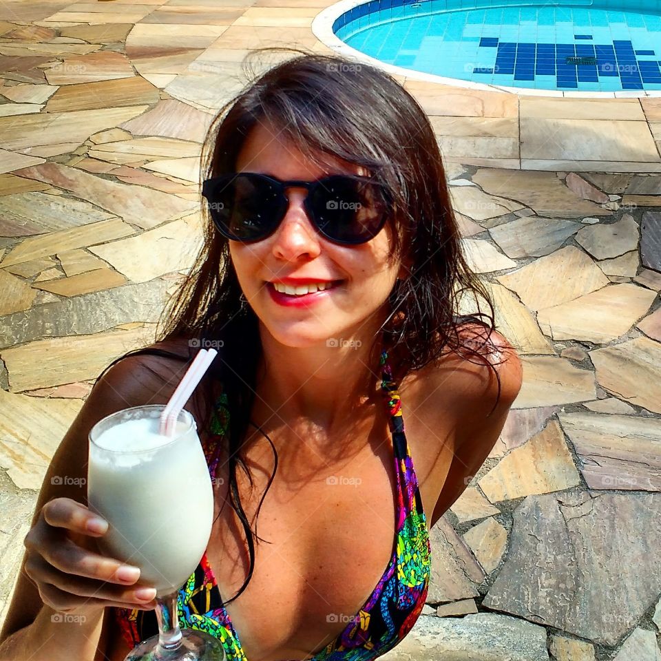 Moça tomando coquetel no resort.