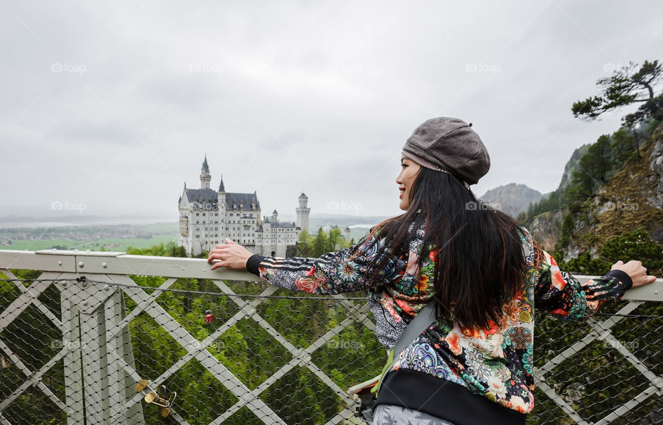 Happy female asian tourist at sightseeing of famous German landmark of Neuschwanstein castle in spring time 