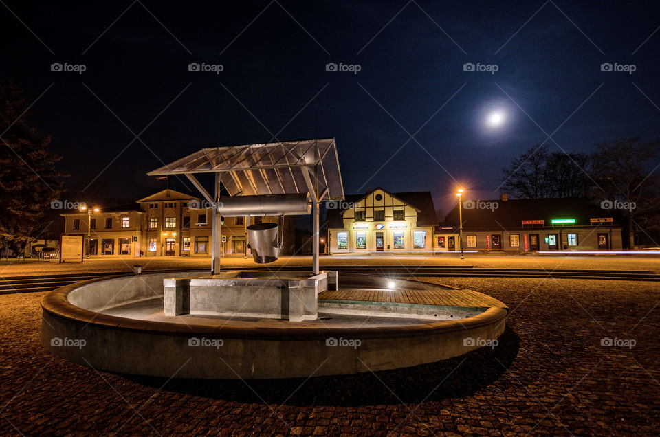 old town market square with a well in the moonlight