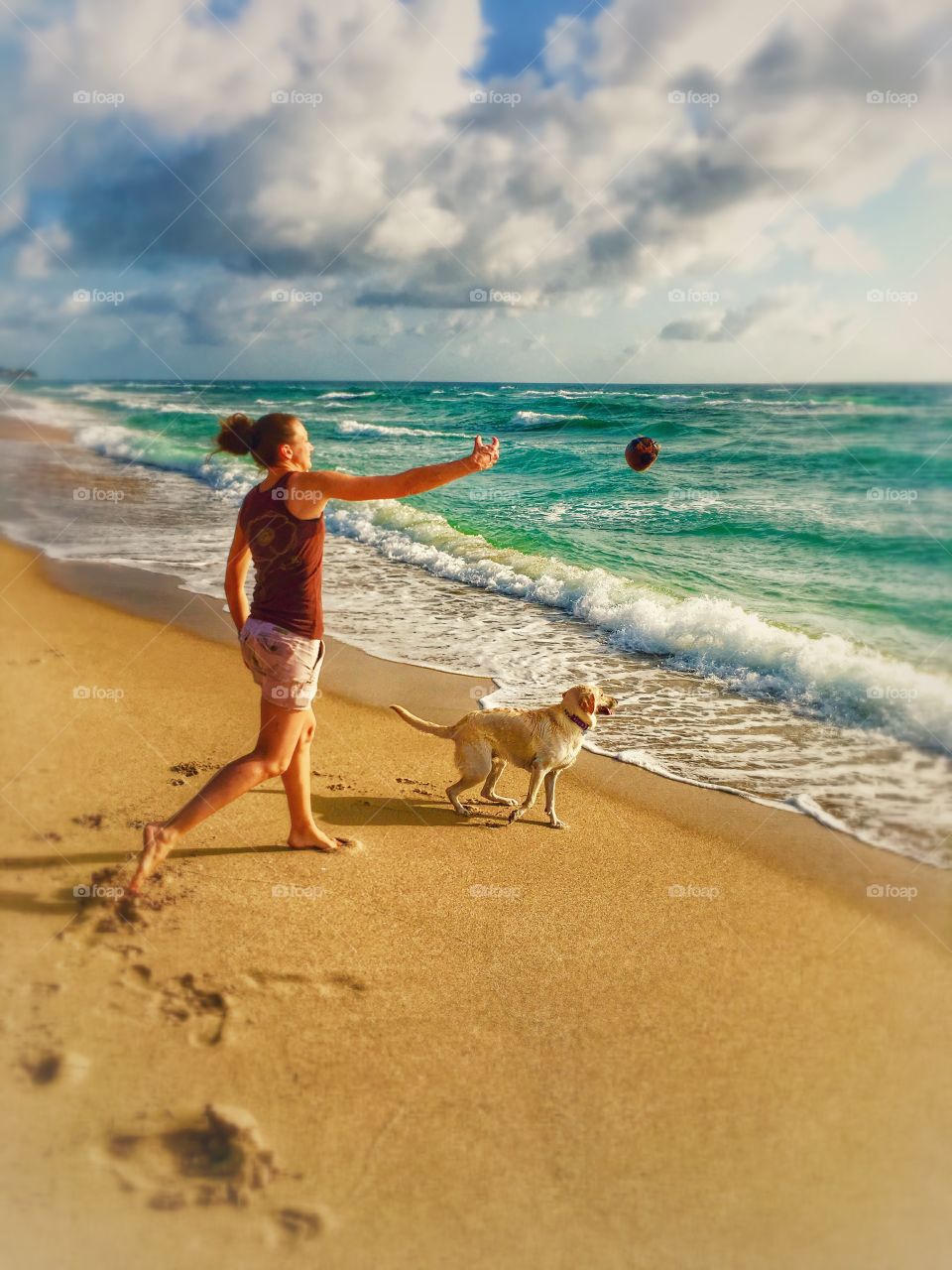 Woman playing with her dog on the beach
