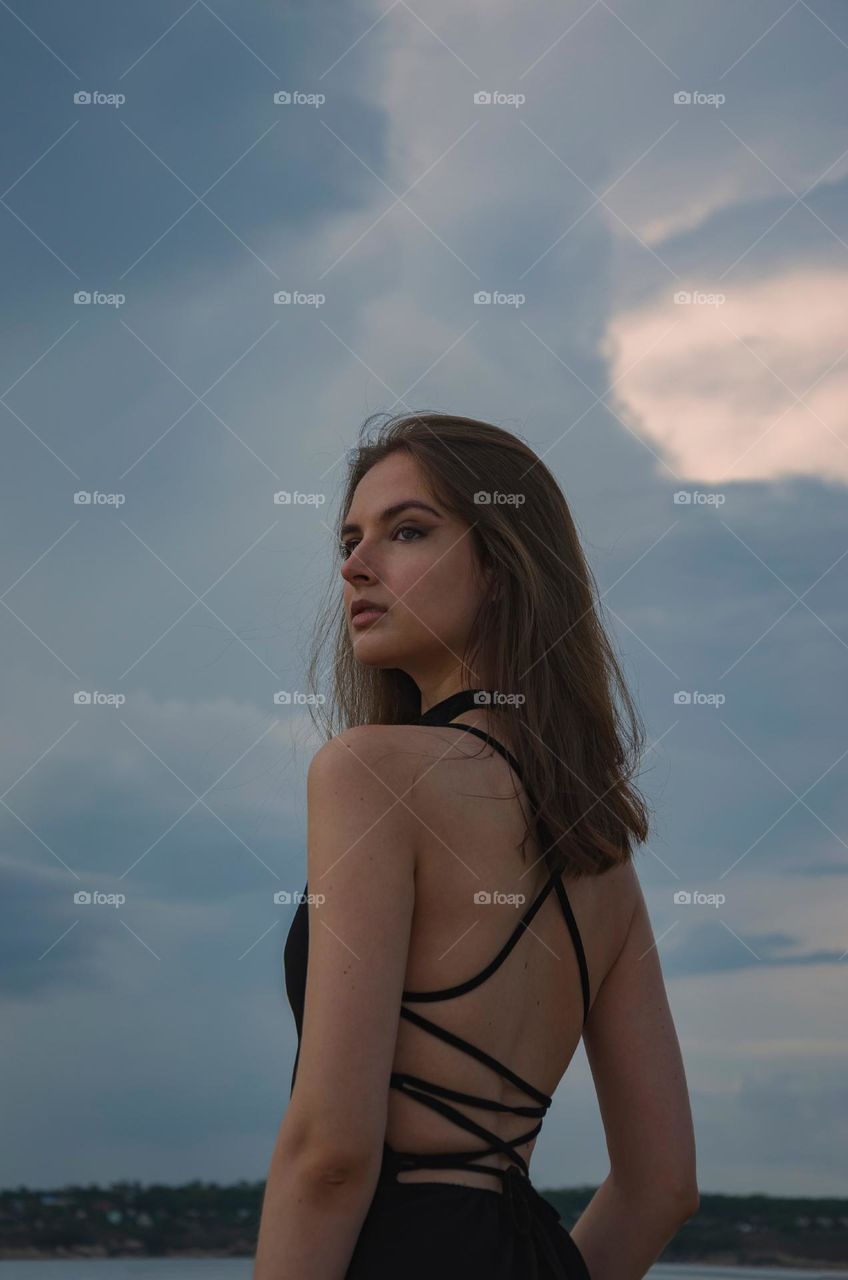 Photo of a girl from the back against a stormy sky