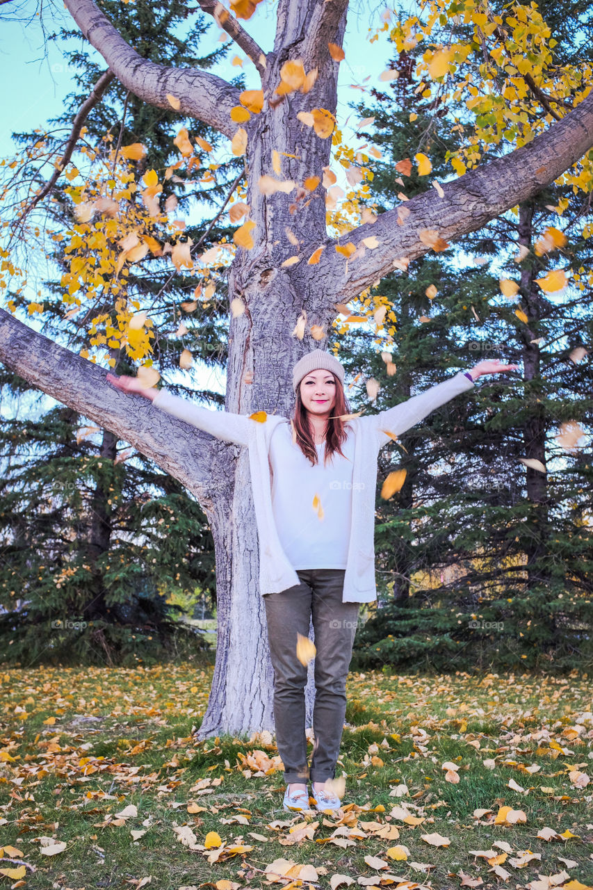 Young woman in the park with falling autumn leaves