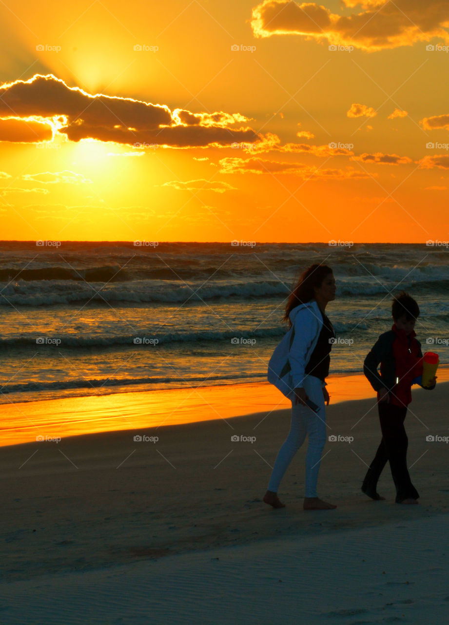Mother and son walk on the sandy beach under a spectacular sunset!