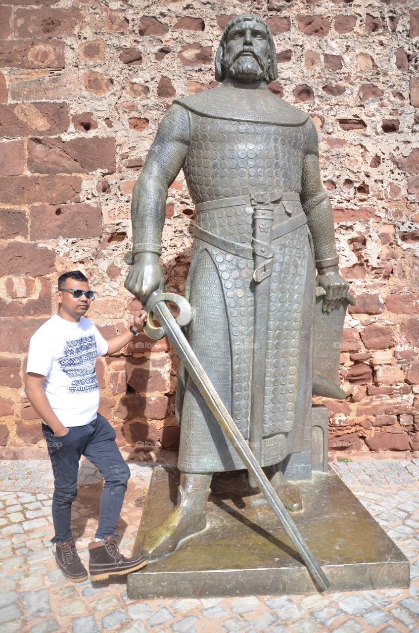Man standing near statue of Sancho in Silves castle, Portugal