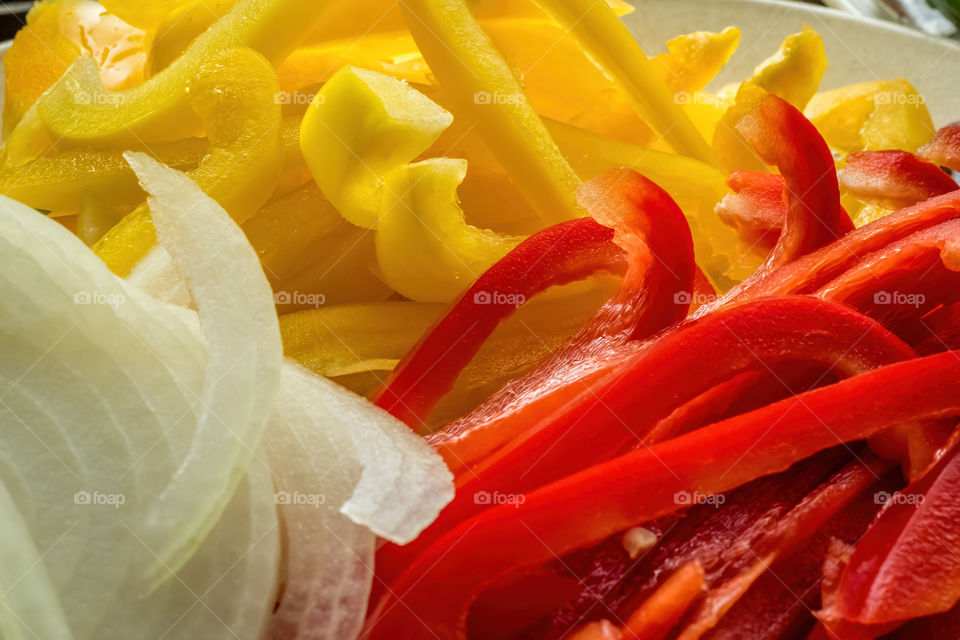 Sliced yellow and red capsicums (also known as peppers or bell peppers) and onion. Note the shallow depth of field.