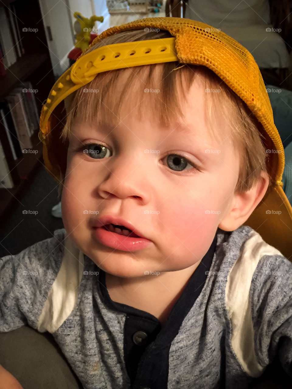 Cute 19 month toddler boy playing with yellow backwards hat 