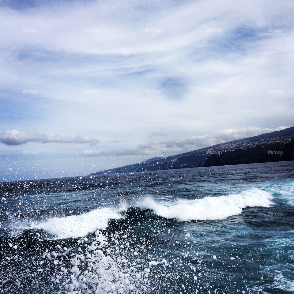 Sea wave against cloudy sky