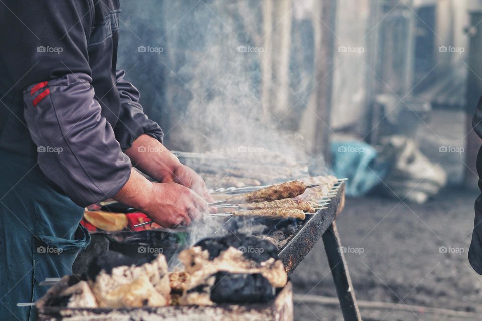 man cook cooking meat on sticks shish kebab asian national dish street food meat on coals in the grill