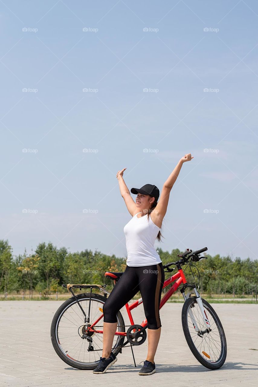 woman in sports clothes and cap riding her bicycle