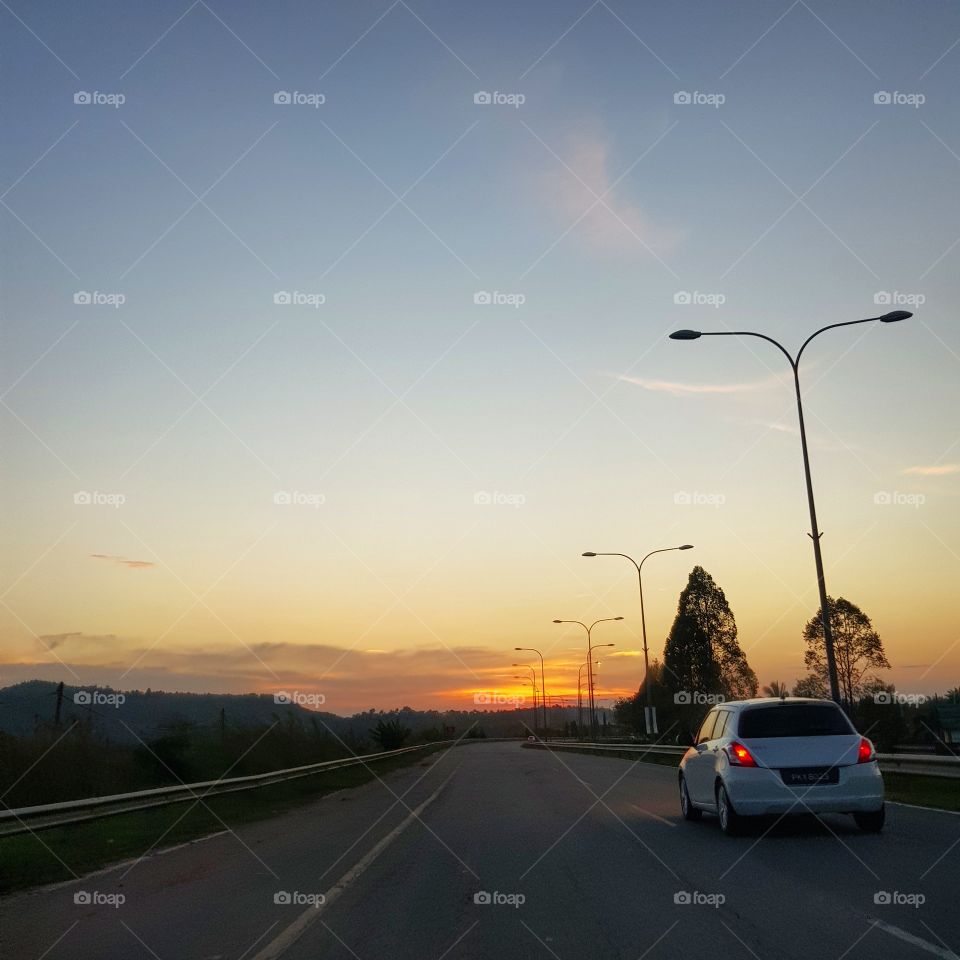 Car is on the road while sunset