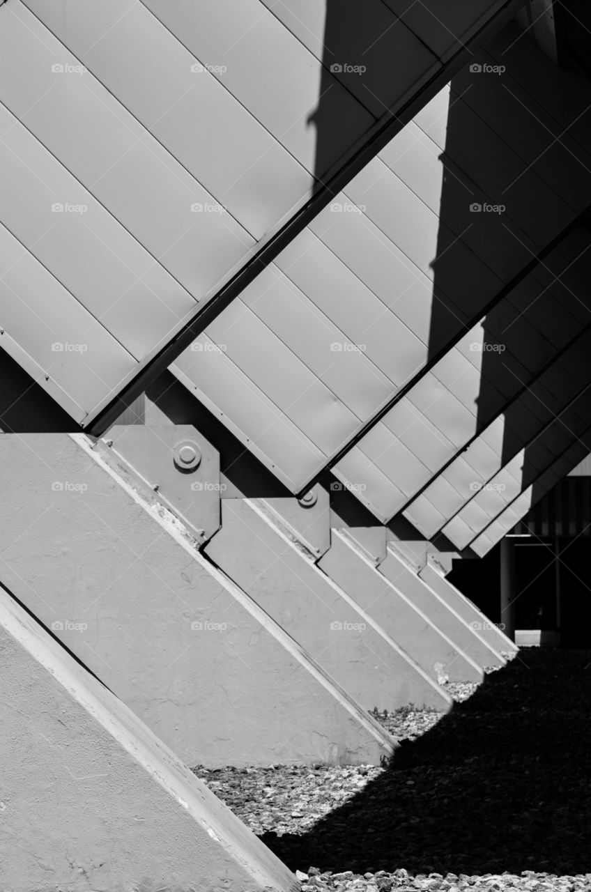 Diagonal architectural metal pillars outdoors with a shadow