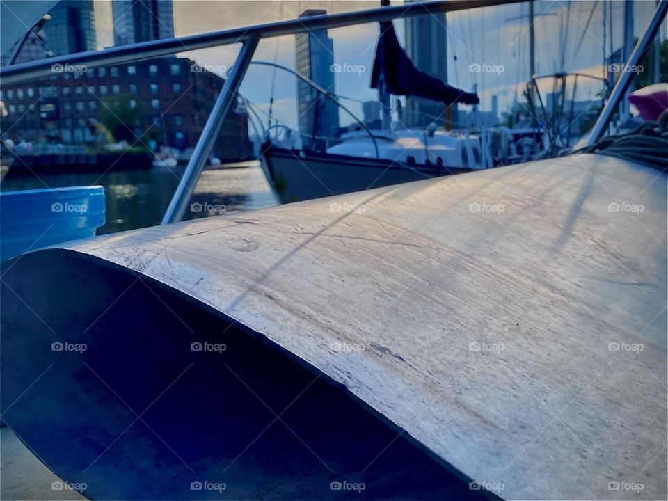 Behind the large folded up aluminum sheet on the front deck of our boat, the “Salvation” you can see the expanse of the “harbor area” of “Newtown Creek”. 2022. Hypnotic Productions