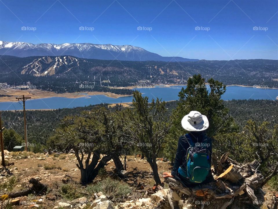 Hiker overlooking a lake with snow capped mountains in the background 