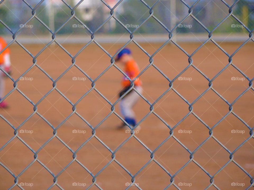 Baseball player playing baseball seen through fence