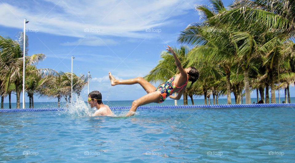 Two brothers having fun in the resort pool on the beach during summer vacation