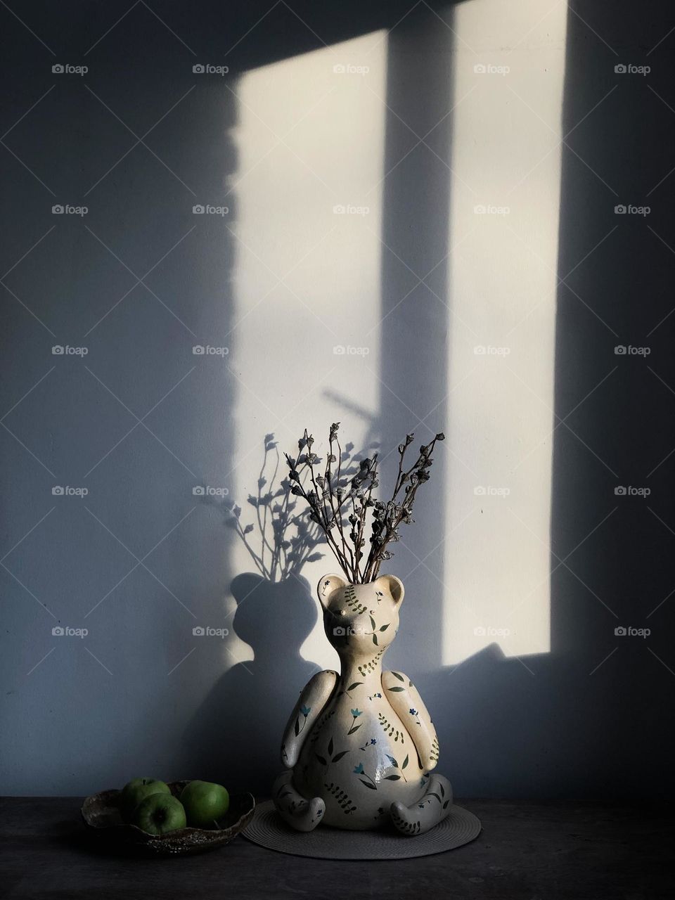 Branches in a vase in the shape of a bear in the sunset light, light and shadow, still life 