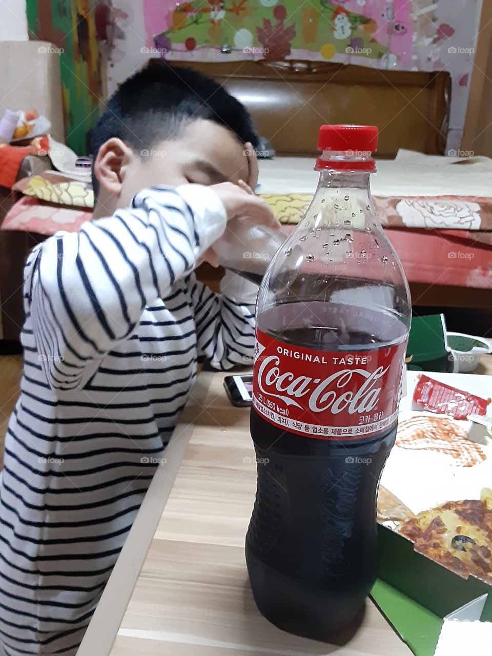watching his fone while drinking coca cola