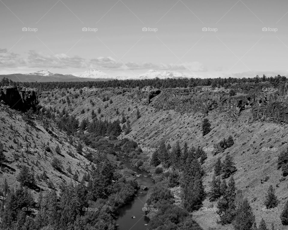 The Deschutes River winds through a canyon in Central Oregon with Cascade Mountains in the background 