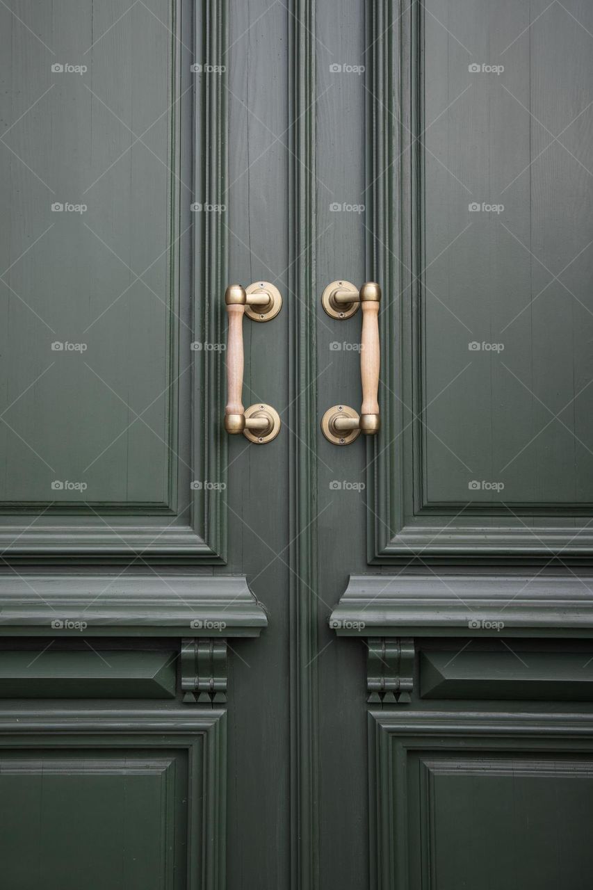 Golden door handles on green wooden doors.  Vertical shot .