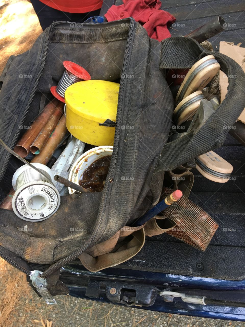 Black canvas tool bag open showing a plumber tools for repair of pipe leak. Plumber variety.