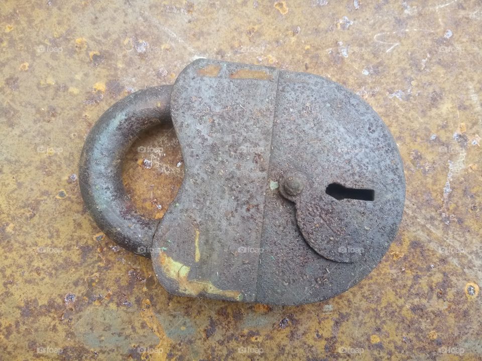 Old large rusty padlock on a rusty metal surface