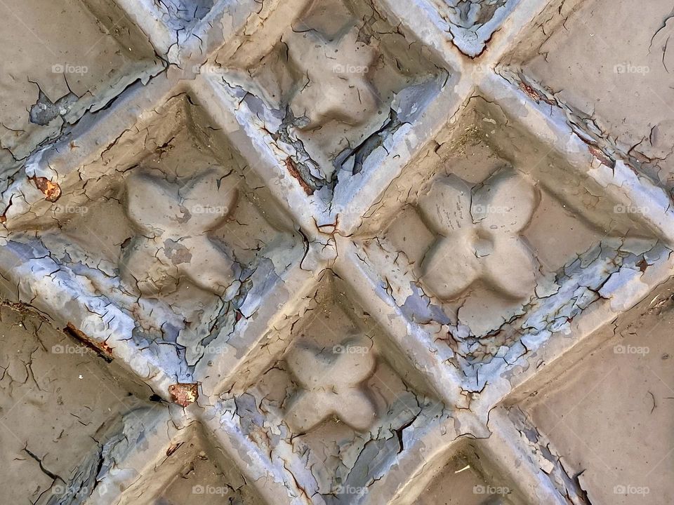 Several layers of cracked paint on a decorative metal fence post