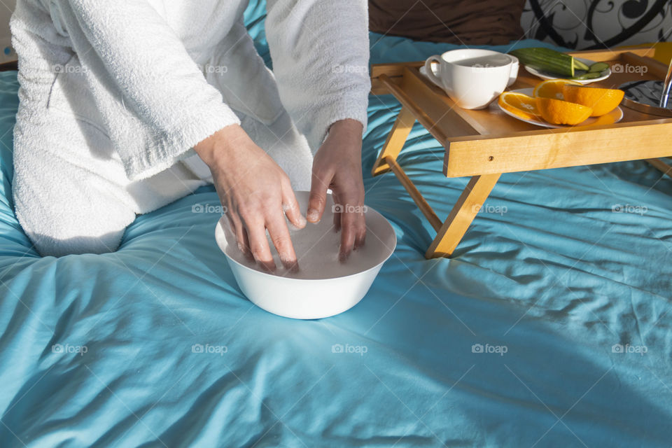 A man at home takes care of himself and does a manicure at home on a blue background and with orange.
