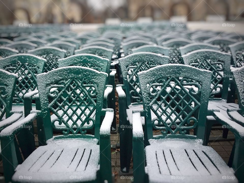 Bunch of green plastic chairs covered in snow 