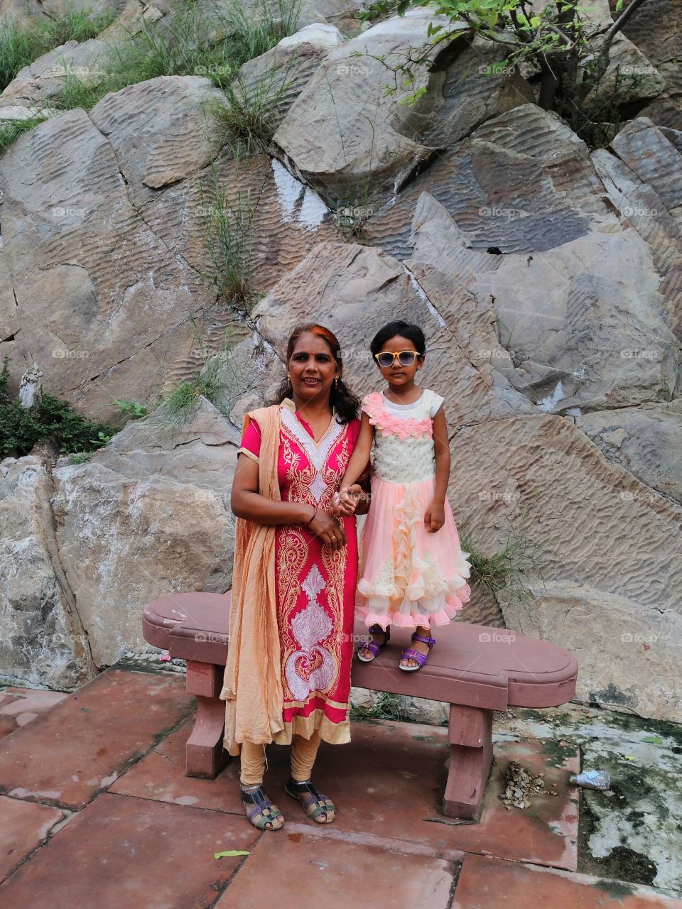 Portrait of little Asian girl on bench with her mother at park