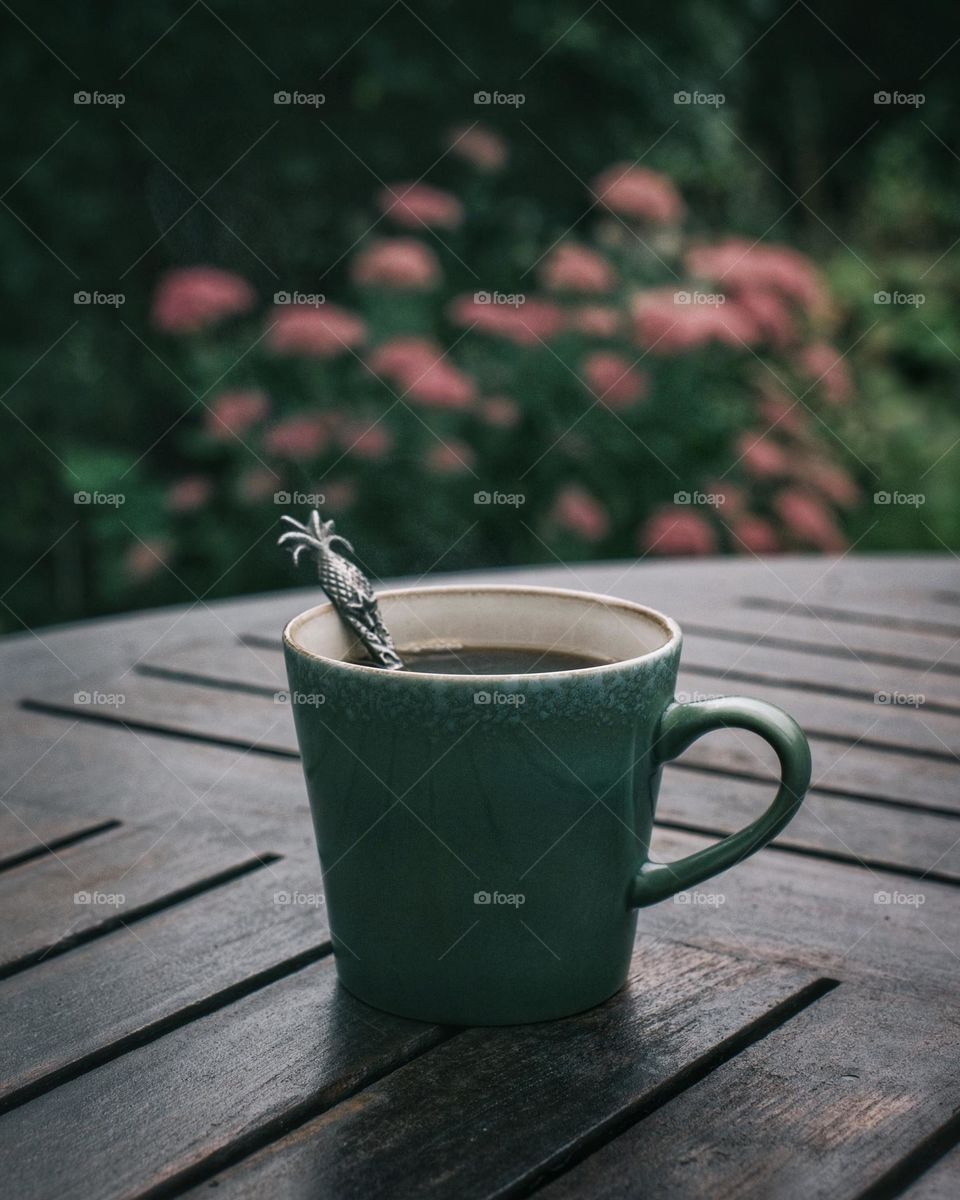 Green coffee cup on a table in a garden 