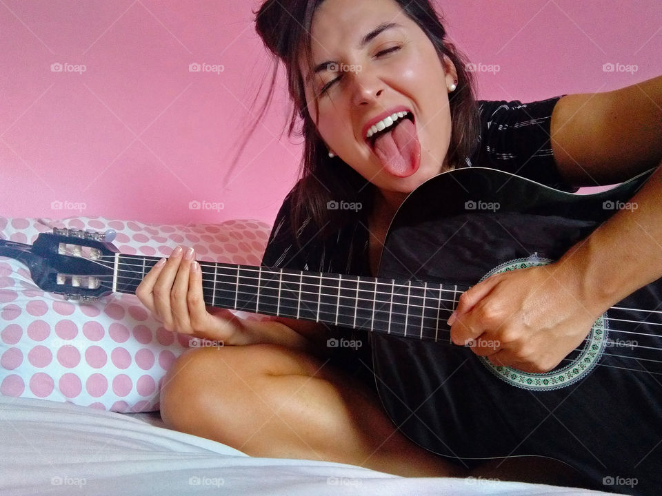 Girl playing the guitar with her tongue out