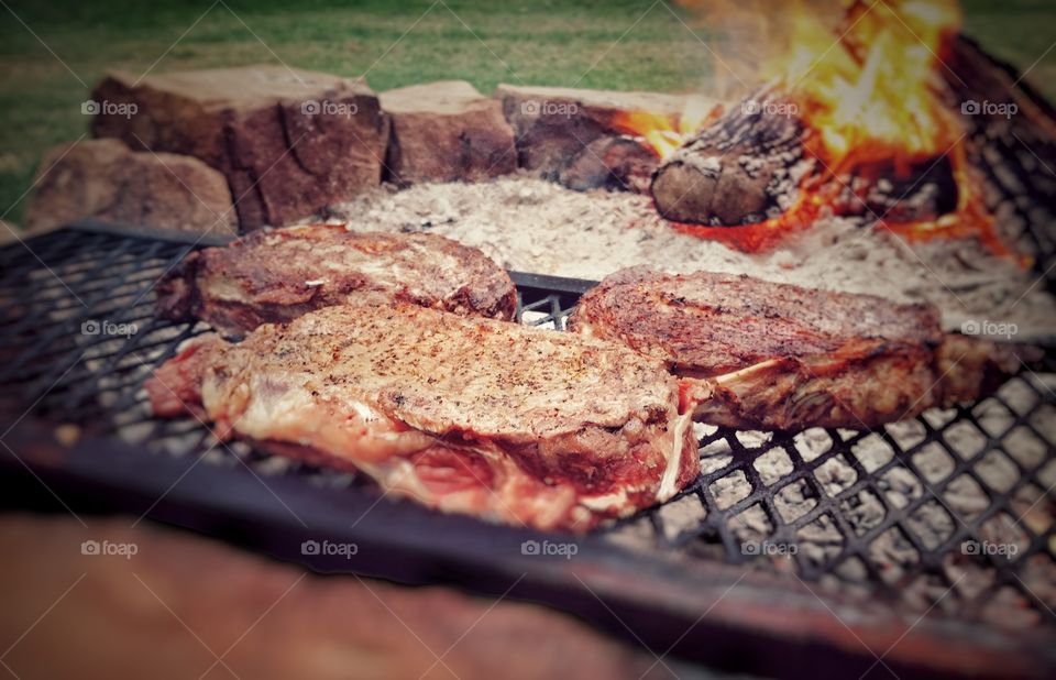 Steaks being grilled over an open fire pit American traditional favorite dish