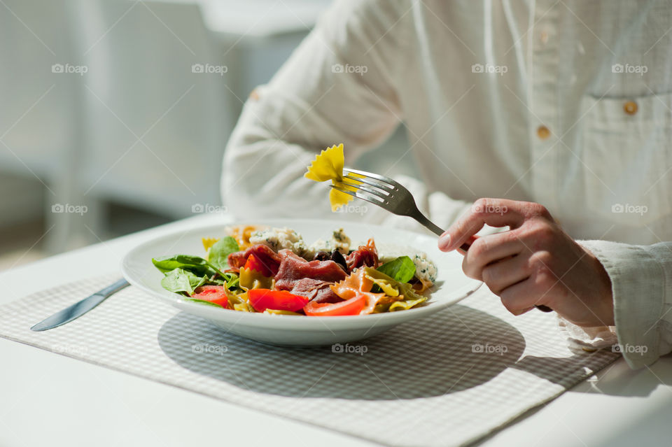 close-up of a young man eating a salad in a light kitchen