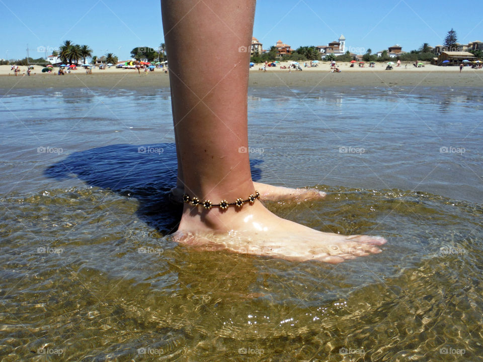 Foot of a girl on the beach with ankle bracelet