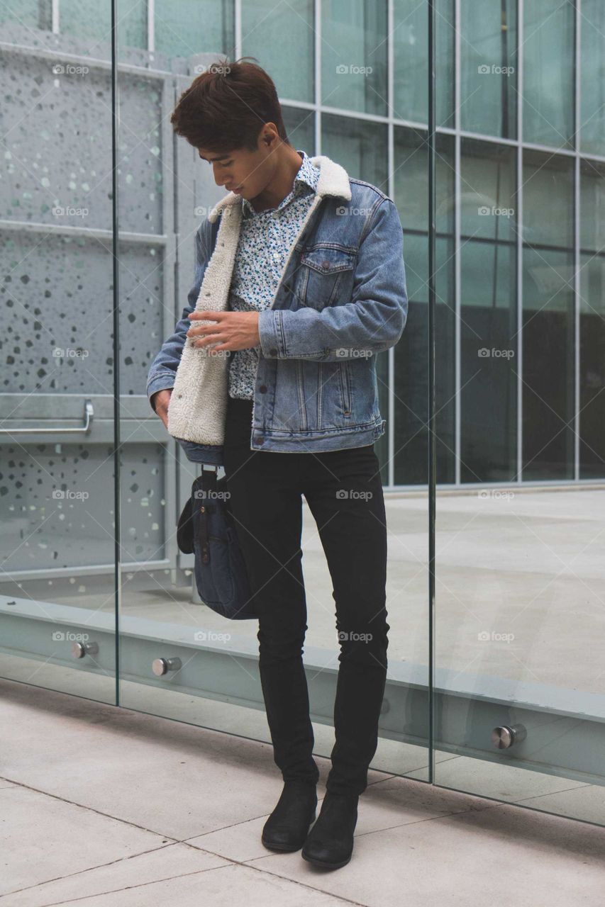 Fashionable hipster male model in urban location, checking his bag, front view, attractive