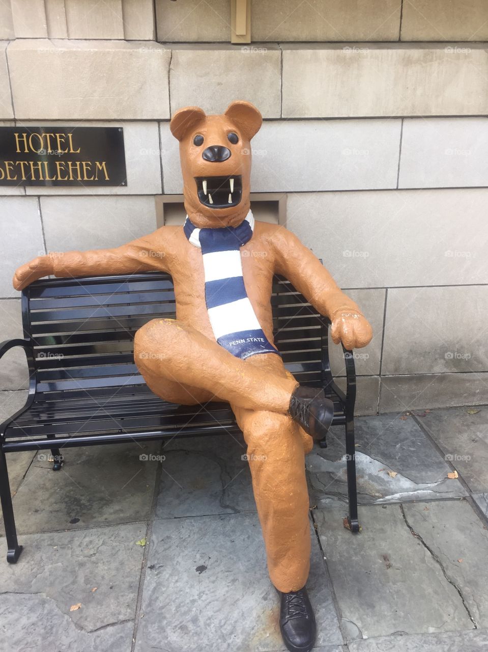 Statue of a bear sitting on a bench