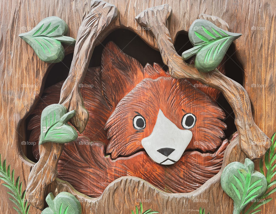 Little fox looking out of his burrow. Woodcarving.